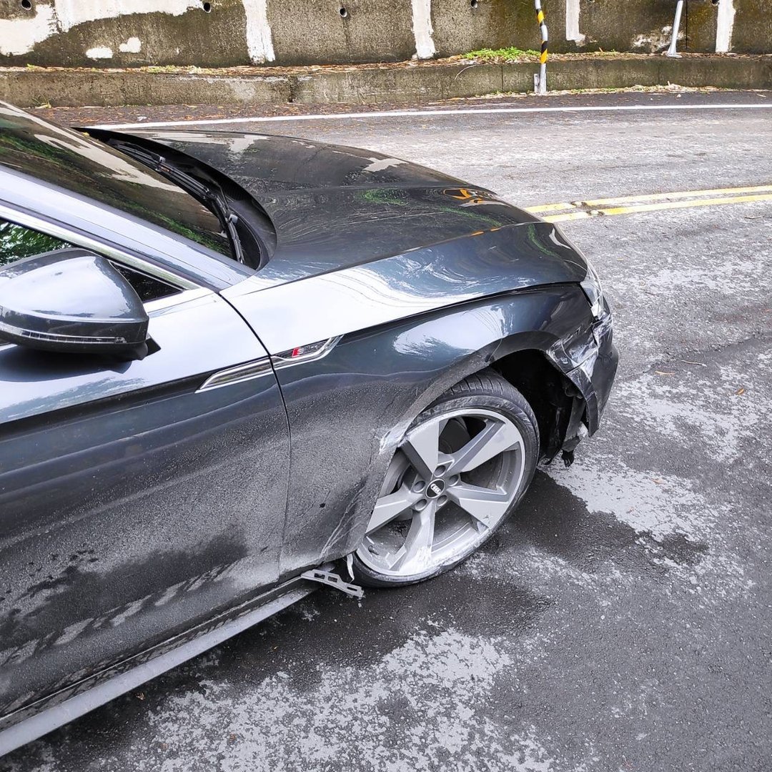 一輛灰色Audi A5轎跑車右側嚴重受損的事故現場，右前輪胎爆裂，車門葉子板變形凹陷。車事通提供專業的Audi A5事故車評估與高價收購服務，擁有完整德系車零件資源。
