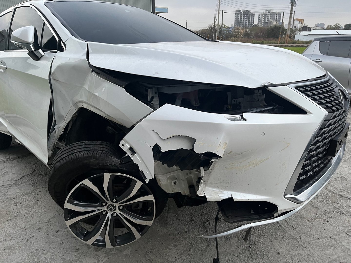 一輛白色Lexus RX豪華SUV前部嚴重受損的事故車,右前輪拱破損露出內部結構,前保險桿變形,引擎蓋凹陷。車事通提供專業的Lexus RX事故車收購服務,24小時全台到府評估。